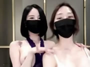 Zwei wunderschöne asiatische Mädchen mit Masken tanzen